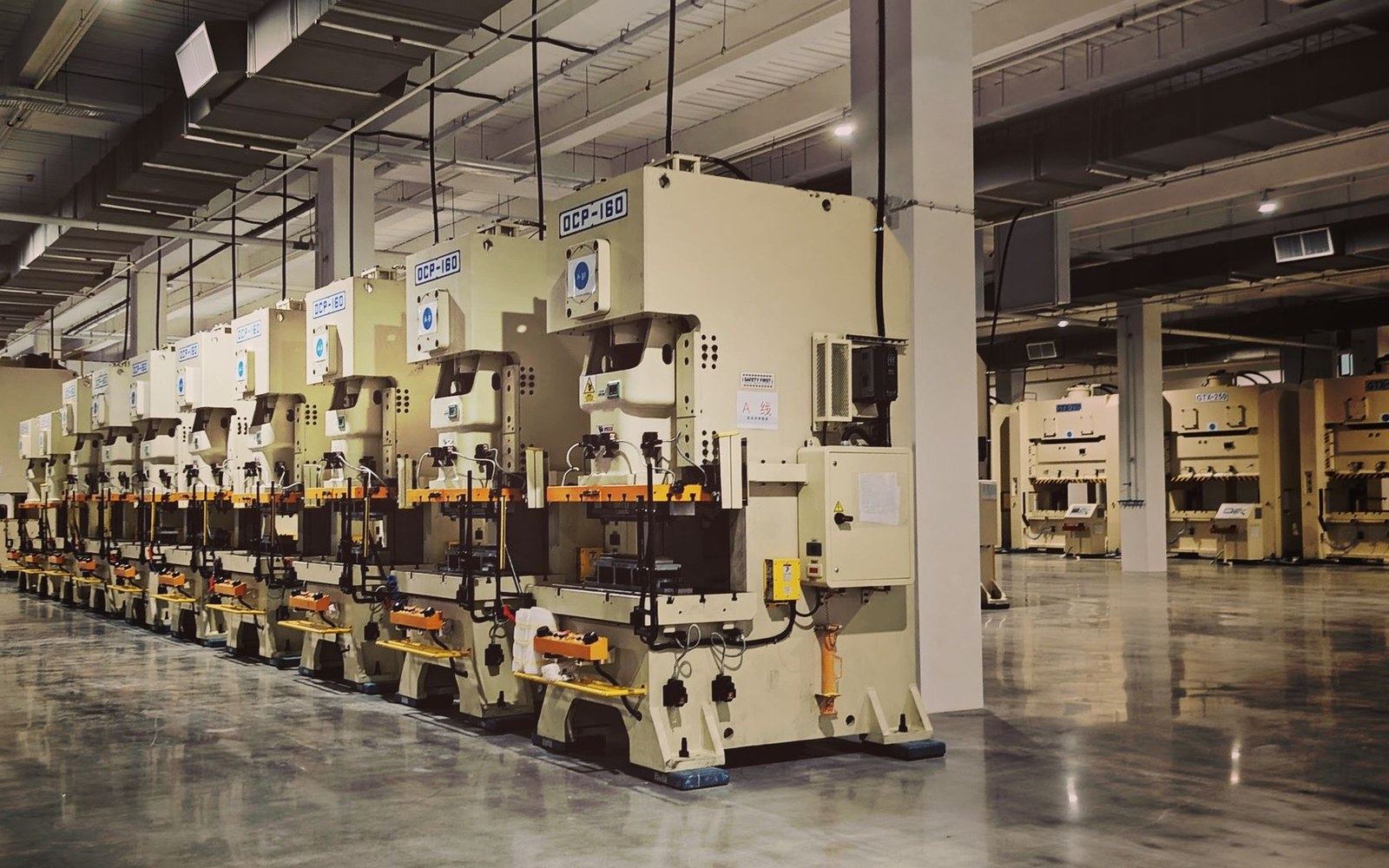Rows of industrial stamping presses lined up on a factory floor